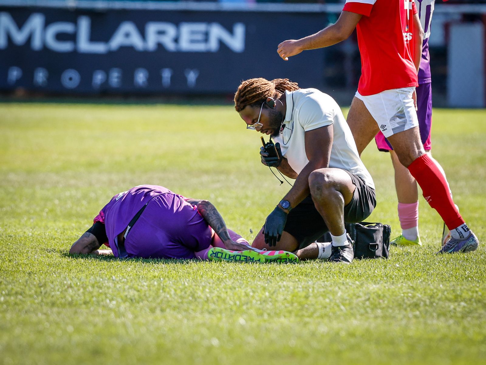 Jeremiah Adegoke assessing an injured footballer pitchside during a match